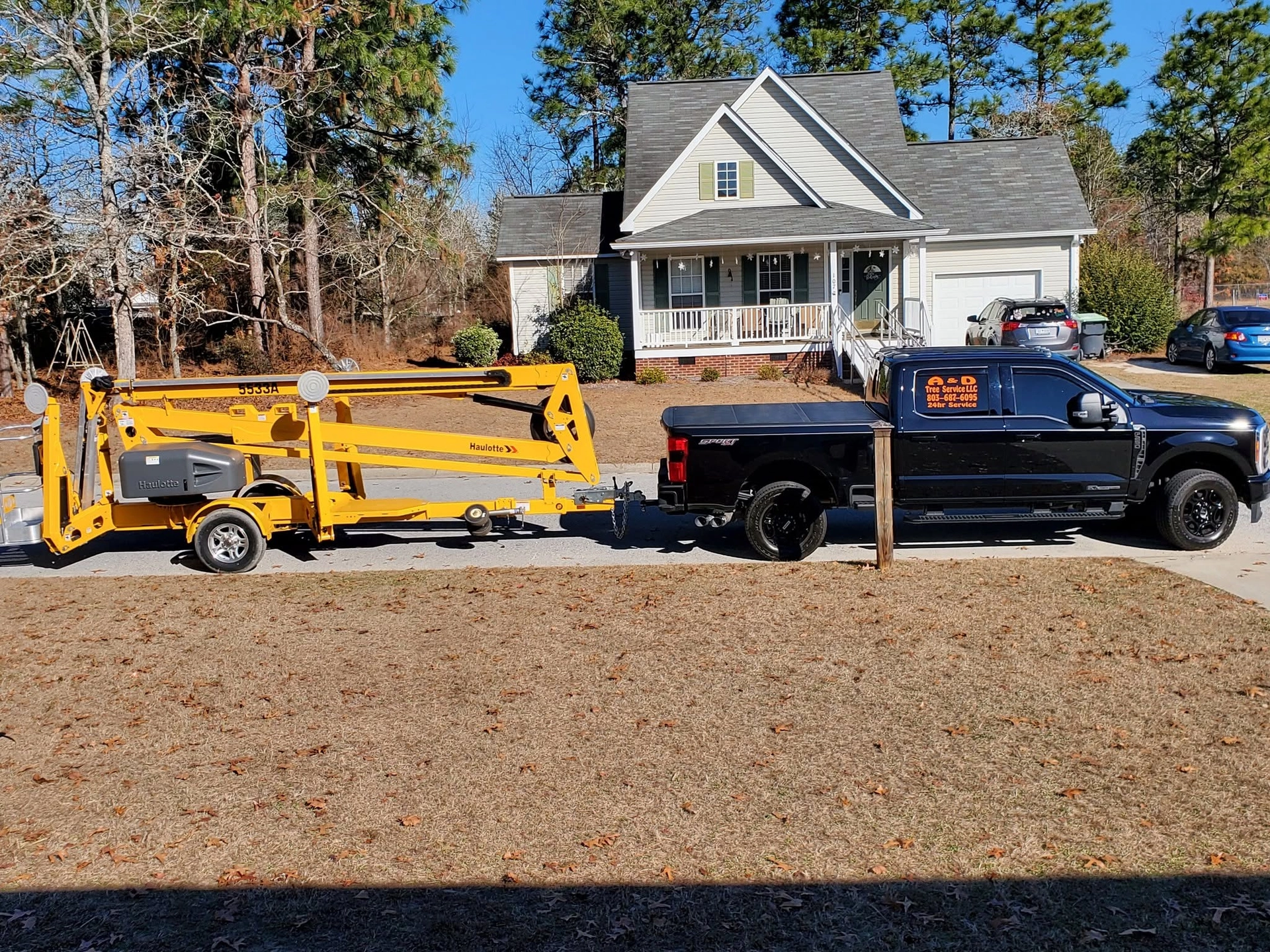 A&D black pickup towing yellow haulotte boom lift gray c