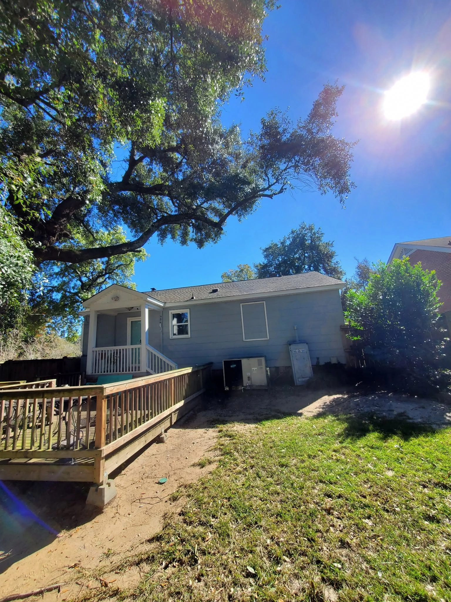 Backyard live oak limbs over light blue house wood deck ramp