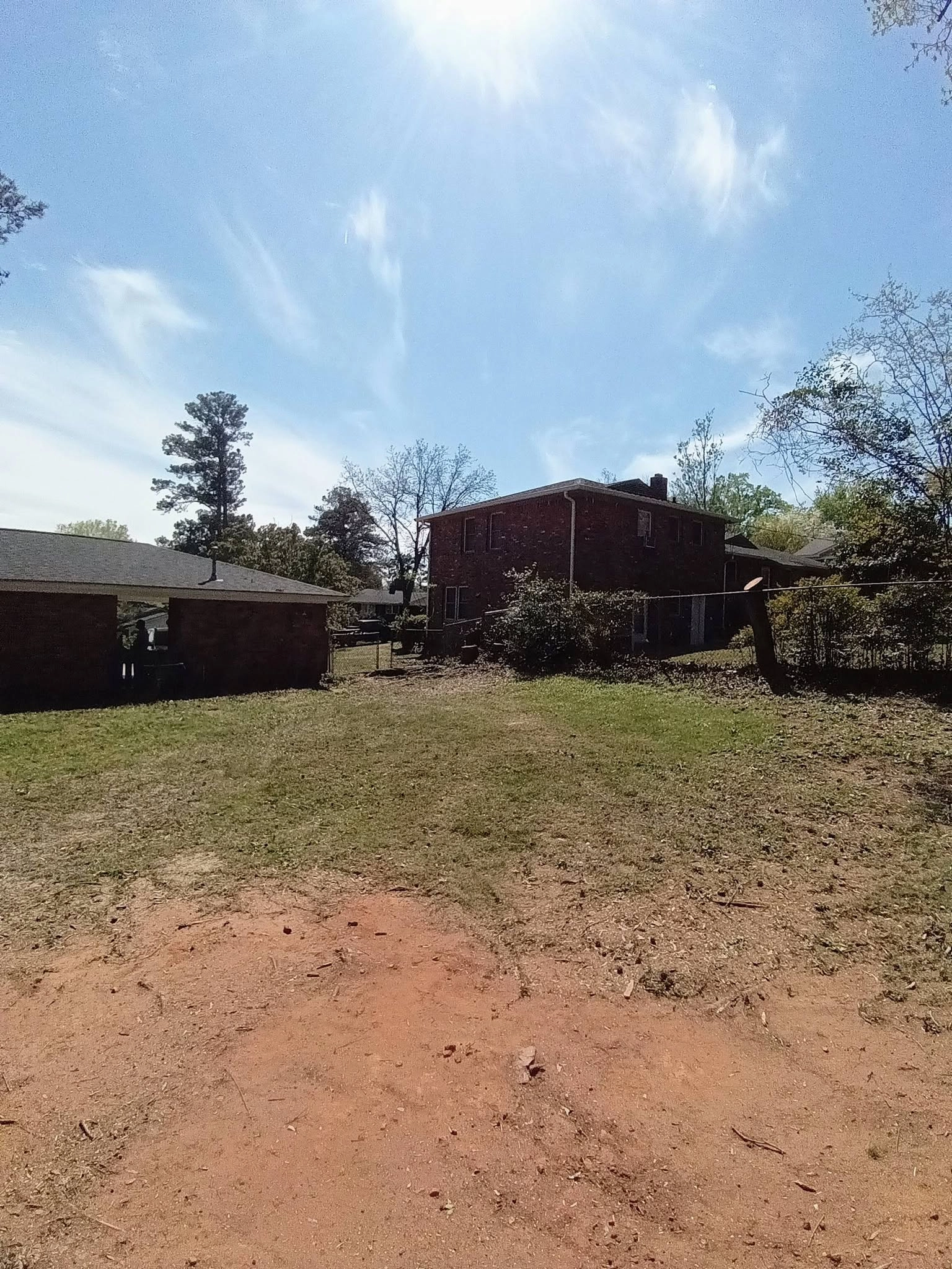 Cleared backyard red clay patch two story brick chain link c