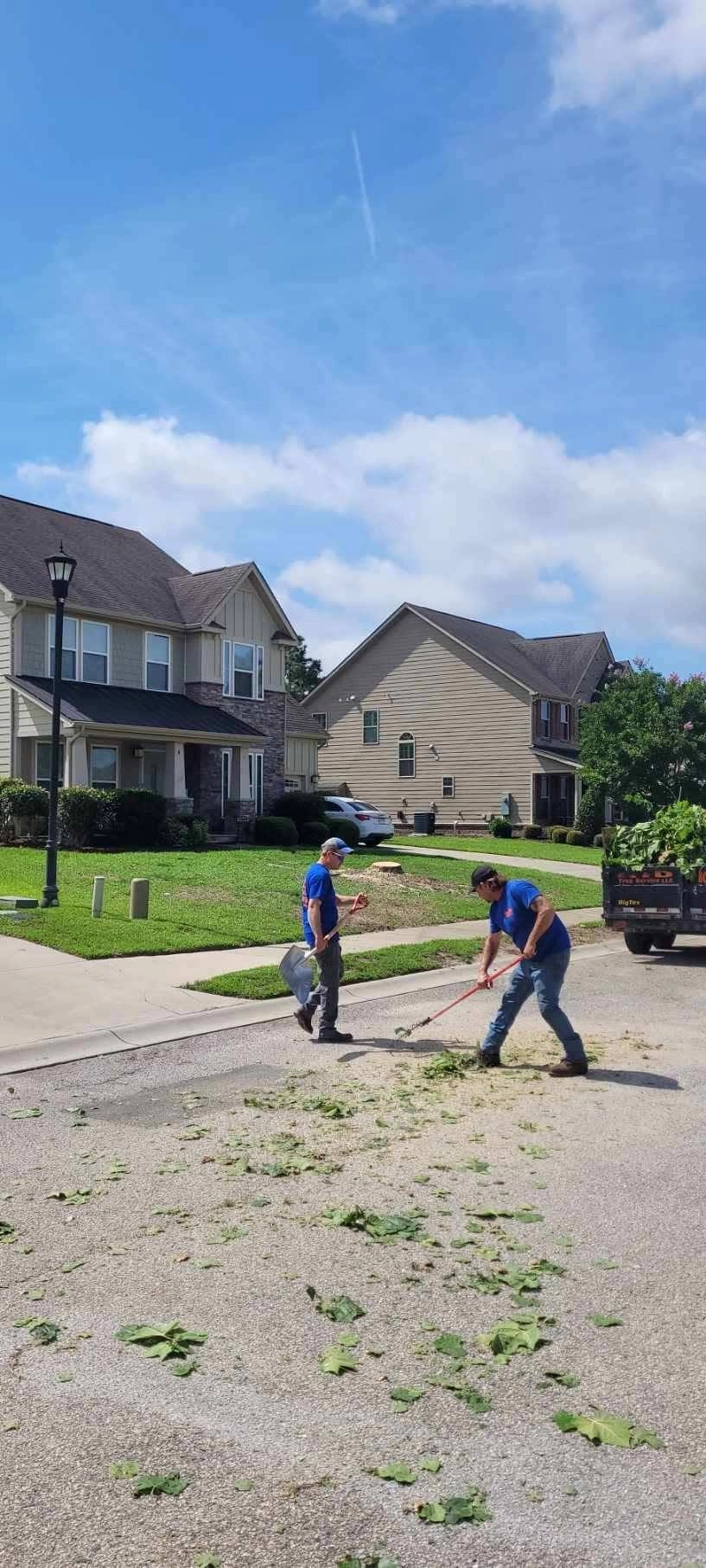 Crew raking leaf debris suburban street two story homes cayc