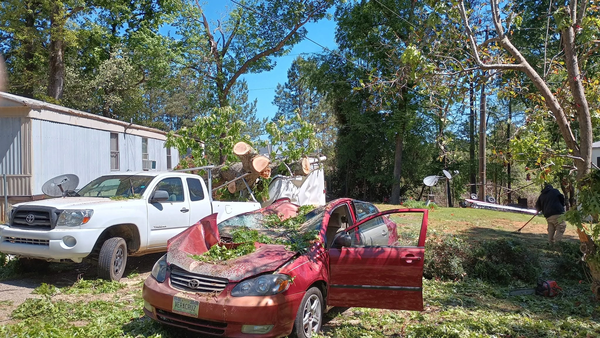 Crushed red toyota sedan white tacoma mobile home storm tree