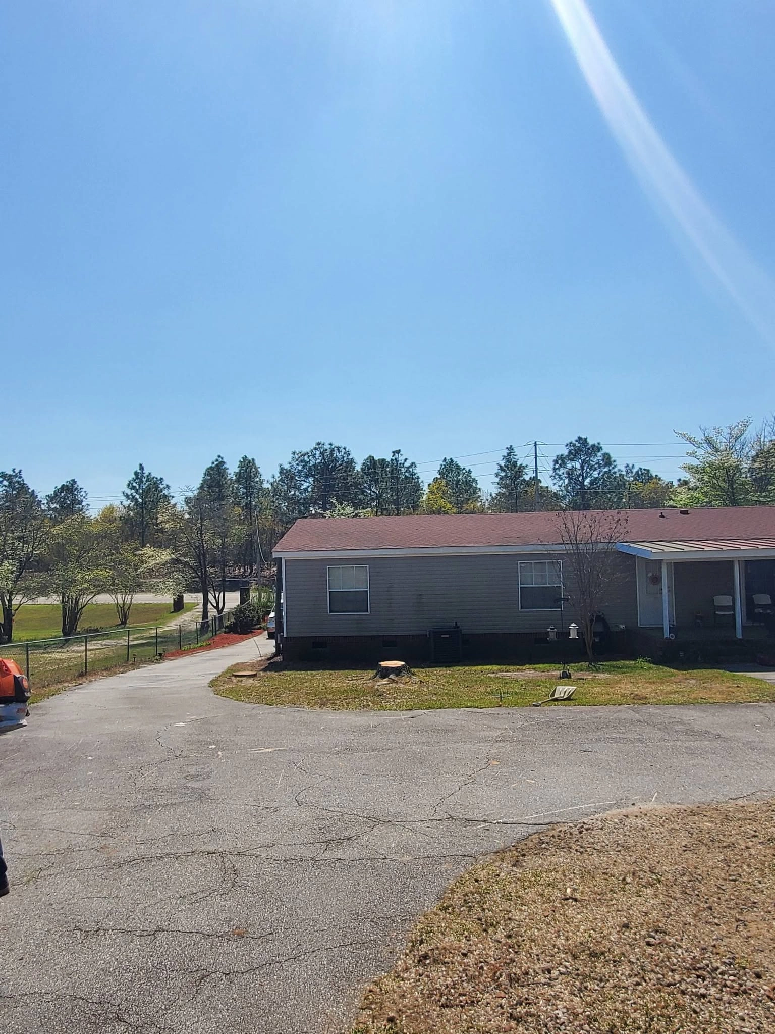 Fresh cut stump front yard gray mobile home red roof drivewa
