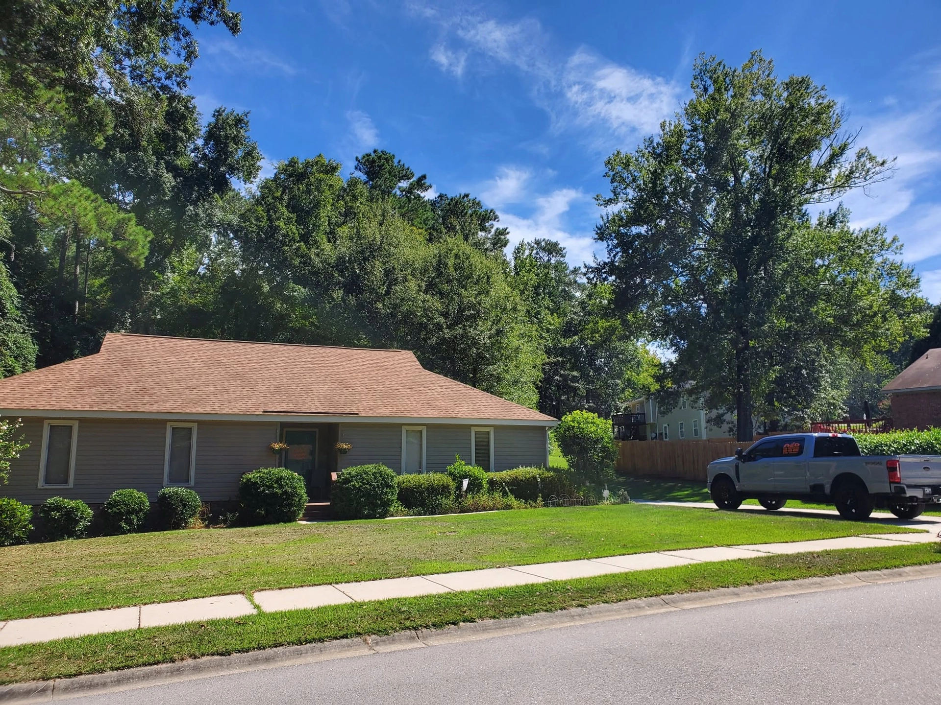 Gray ranch brown roof tree canopy white pickup driveway cayc