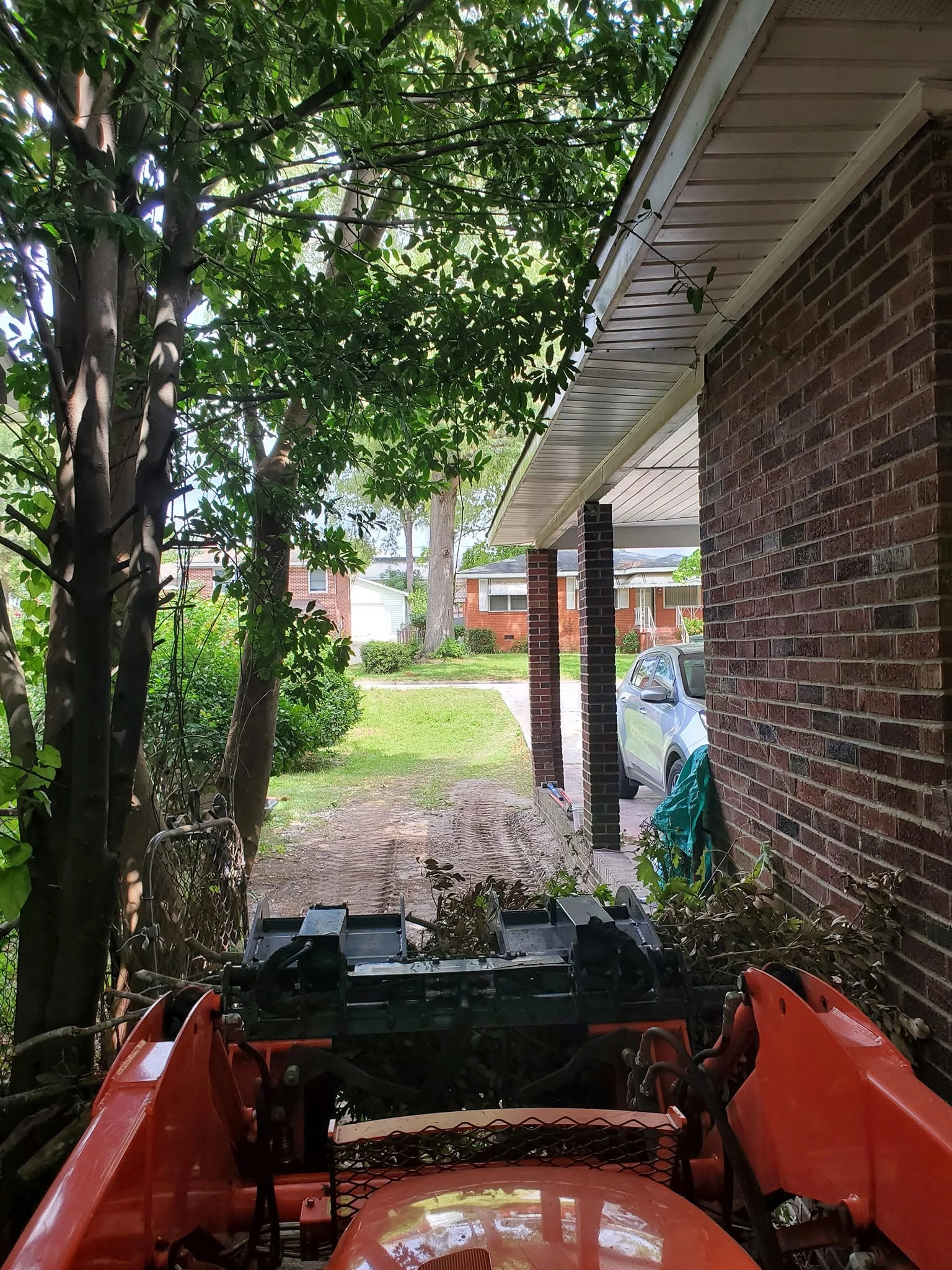 Kubota grapple operator view narrow side yard brick carport 