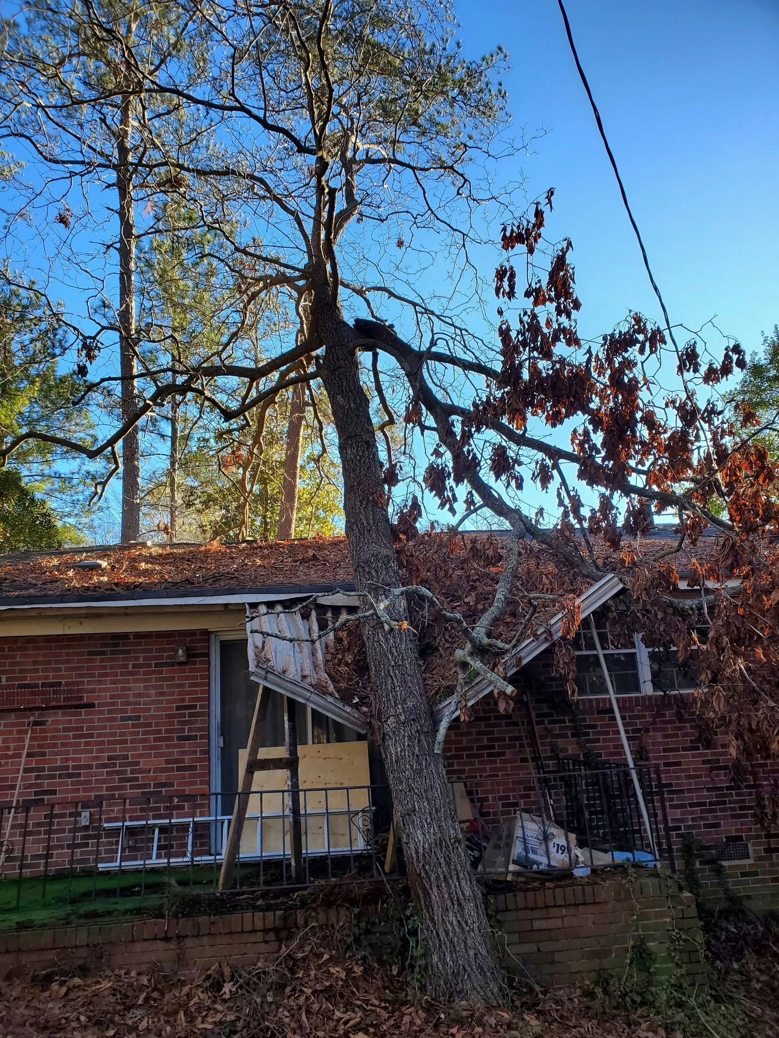 Leaning oak crushed porch roof boarded sliding door brick ho