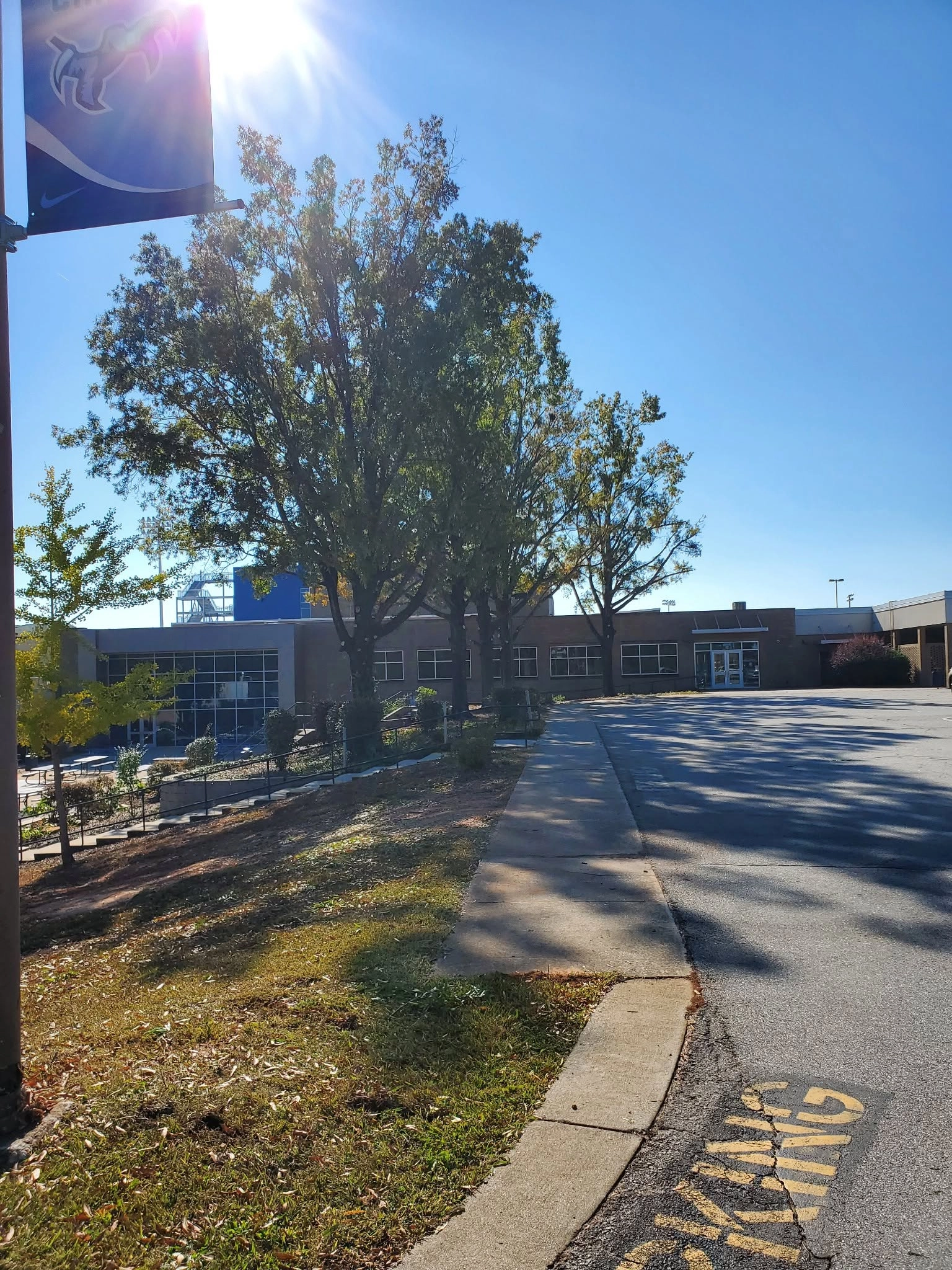 Mature shade trees school entrance parking lot blue banner c