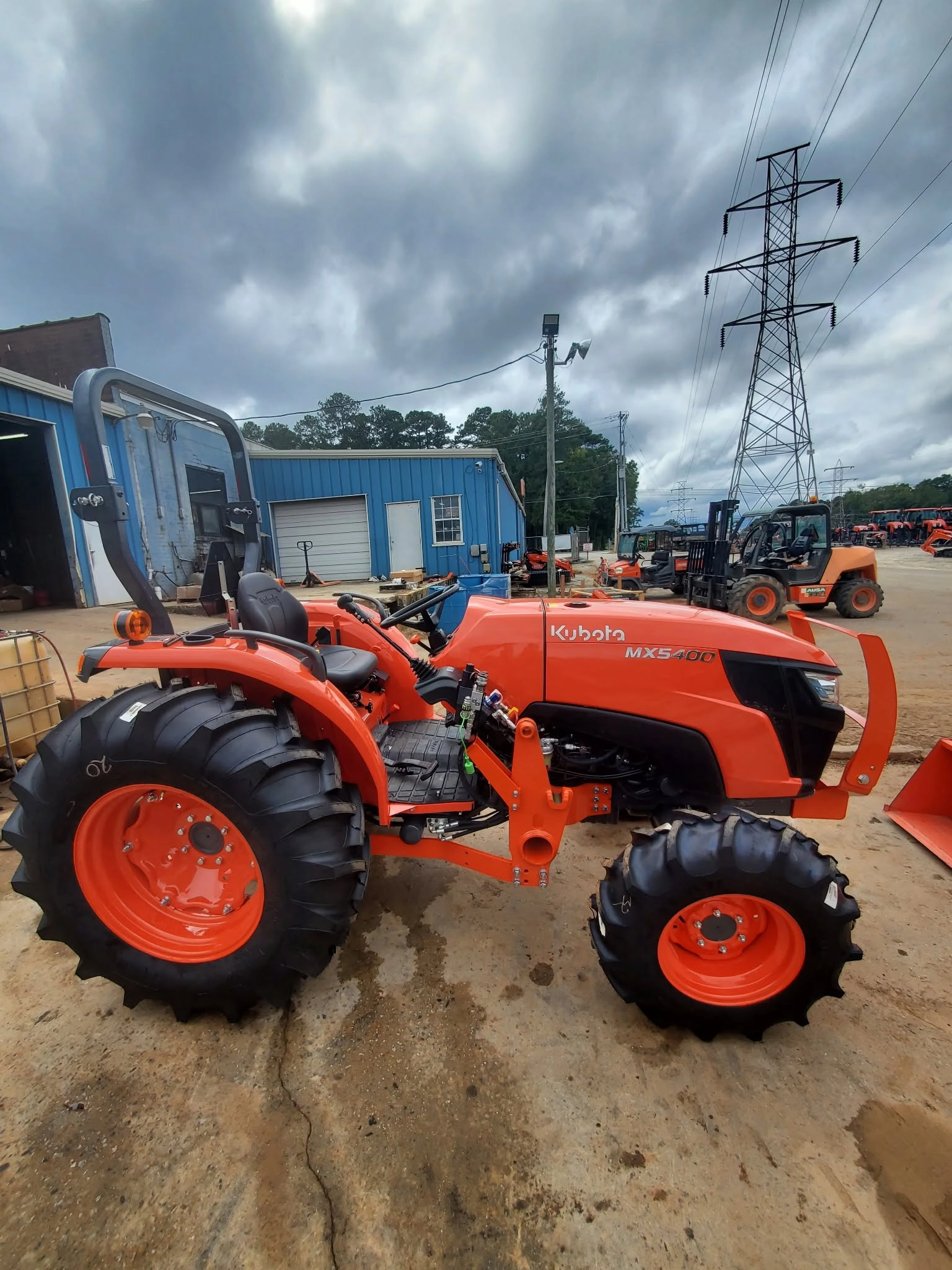 New orange kubota mx5400 tractor dealer lot blue building ca