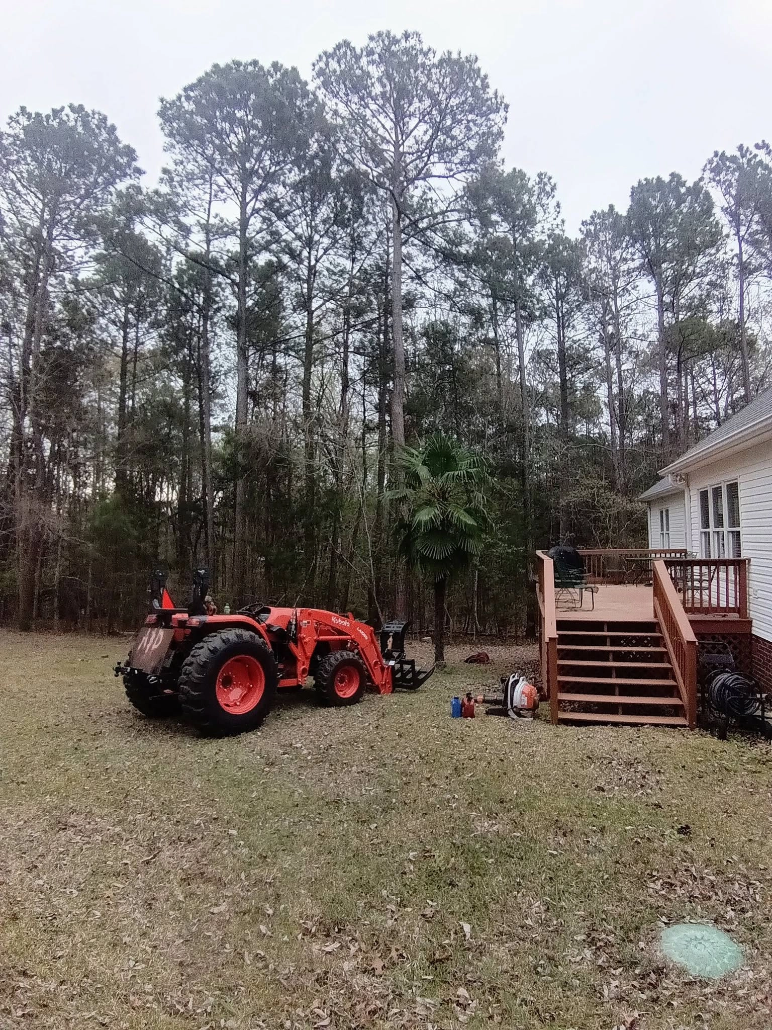Orange kubota tractor grapple backyard deck steps pines cayc