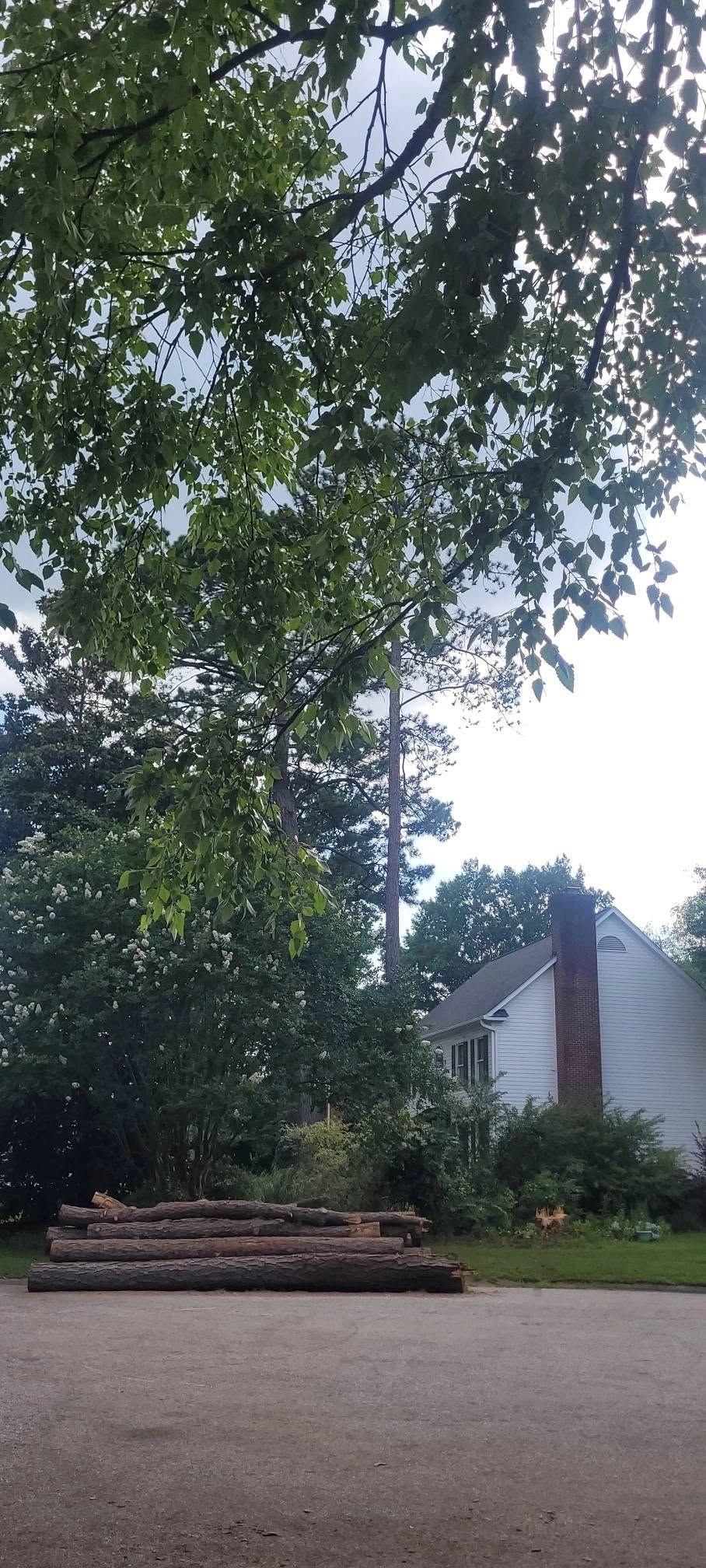 Stacked logs driveway edge brick chimney white house crape m