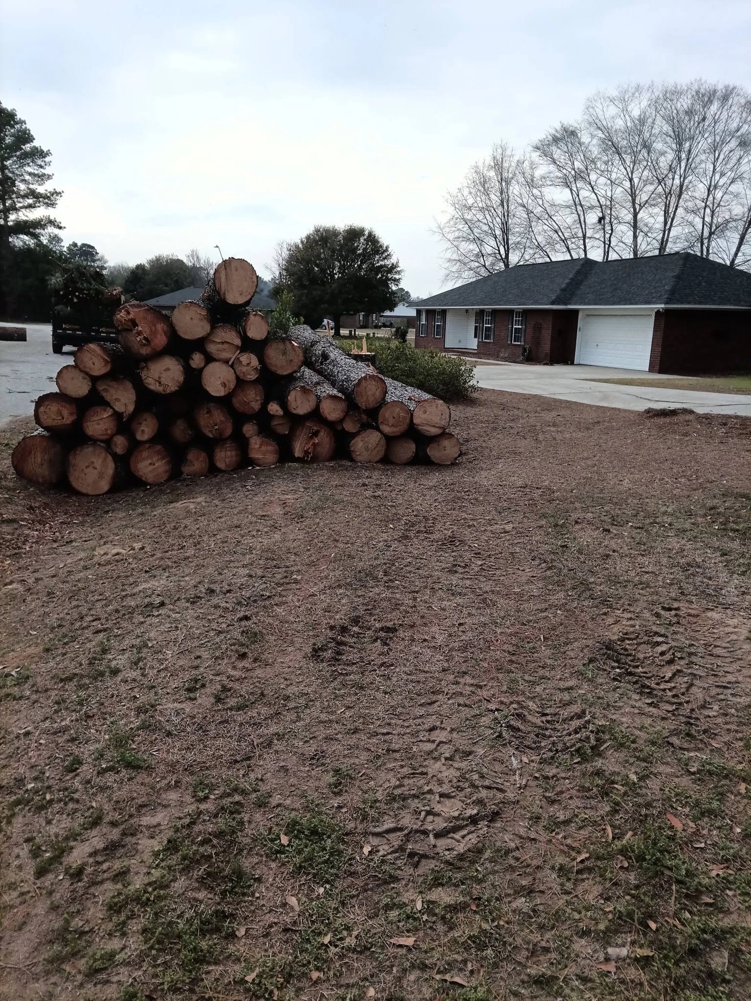 Stacked pine logs bare dirt yard brick ranch garage west col