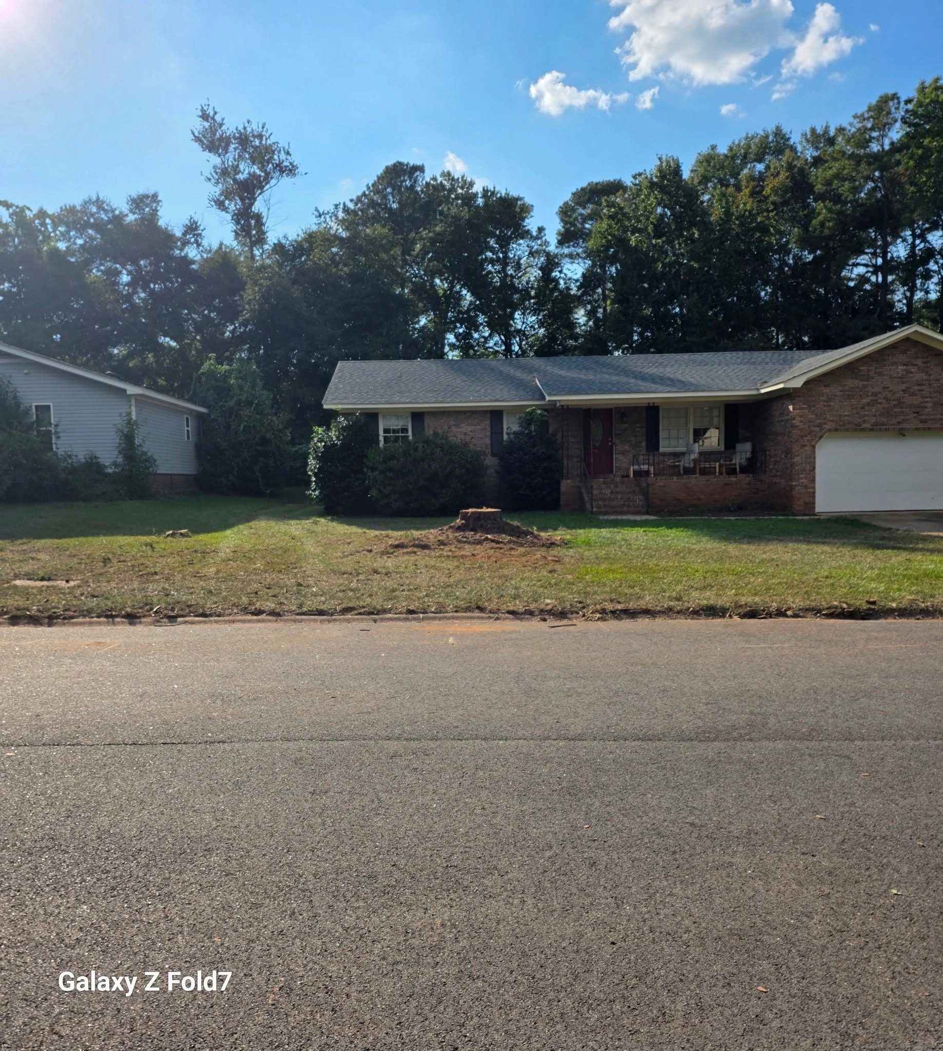 Street view brick ranch red door fresh cut stumps front lawn
