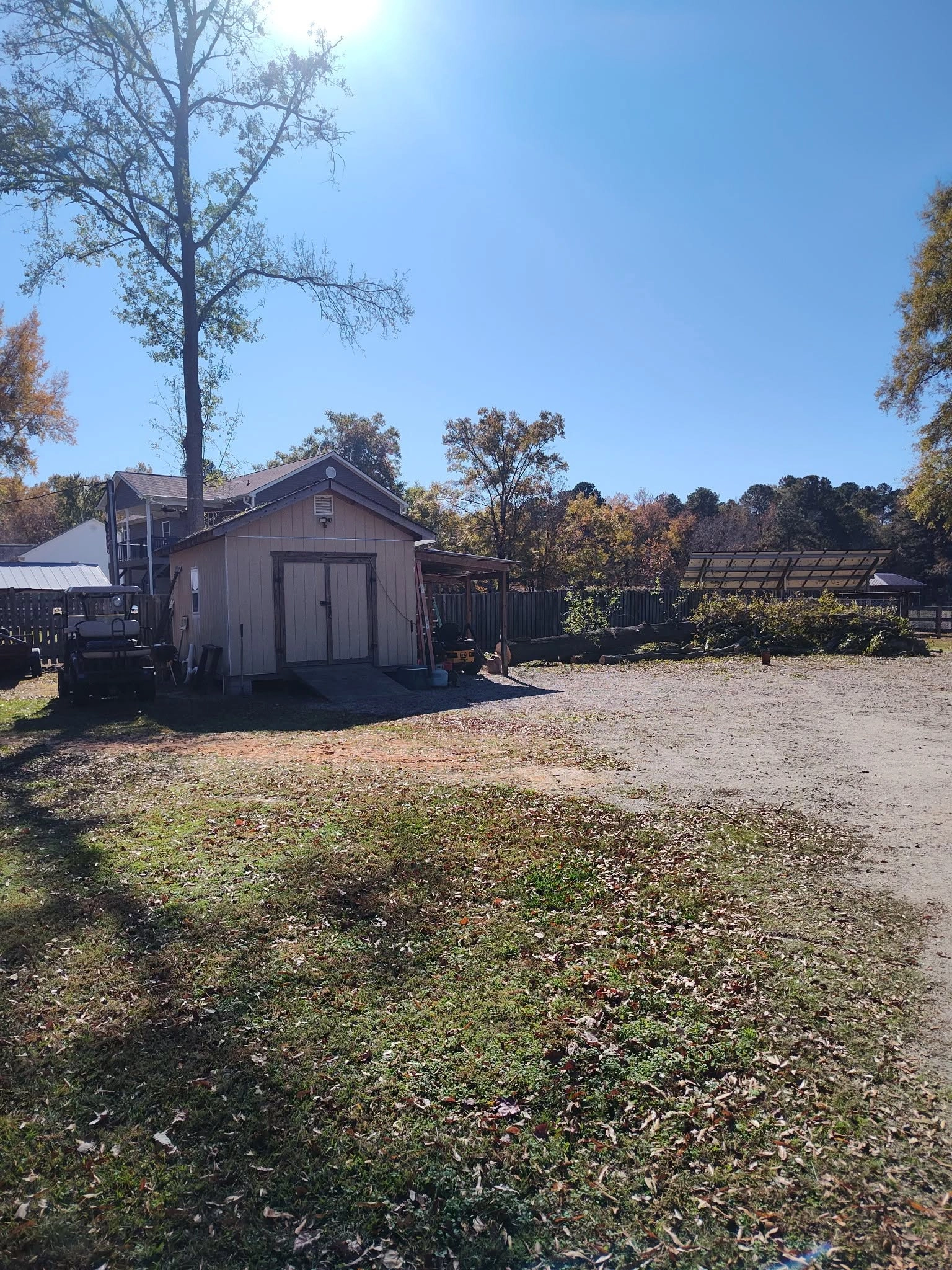 Tan storage shed golf cart cut logs brush pile dirt yard cay