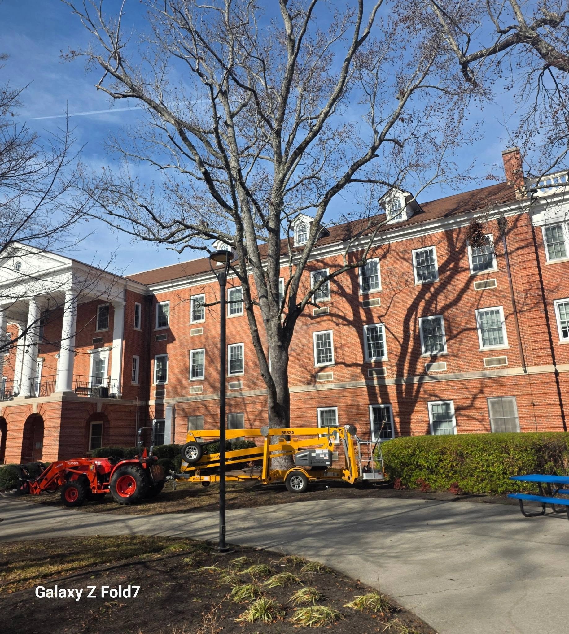 Yellow towable boom lift kubota bare oak brick campus buildi